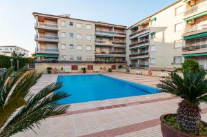 a swimming pool in front of some apartment buildings at Near beaches large private patio, aircon & community pool in Comarruga