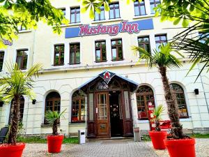 ein Gebäude mit einem Gasthaus mit Palmen davor in der Unterkunft MUSTANG INN am Großen Garten in Dresden