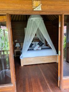 a bed with a canopy in a room at The Niti Hut's Lembongan in Nusa Lembongan