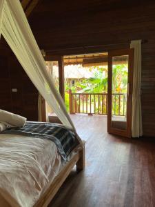 a bedroom with a bed and a door to a porch at The Niti Hut's Lembongan in Nusa Lembongan