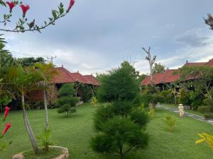 a garden with trees and houses in the background at The Niti Hut's Lembongan in Nusa Lembongan
