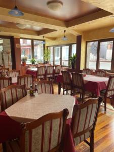 a dining room with tables and chairs and windows at MB Hotel in Žabljak