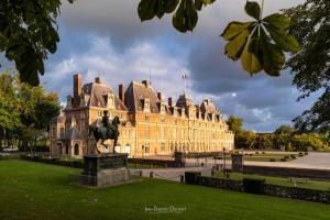 un grande edificio con una statua davanti di IDÉALEMENT SITUÉ "LE STUDIO" Les Locations ISAHORA sont aussi à 2 pas du Château d'Eu, des Falaises du Tréport, de MERS les Bains et aux portes de la BAIE DE SOMME a Eu
