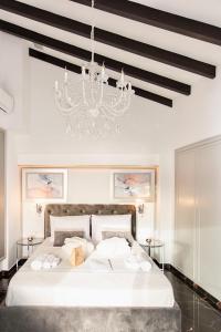 una camera da letto con un grande letto bianco e un lampadario a braccio di Mare suites 1 a Chania
