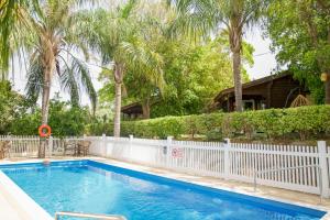 a swimming pool with a white fence and trees at Eden Ramot Chalets in Moshav Ramot