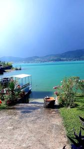 a lake with a pier and flowers on the shore at Lejla apartmani - Jablaničko jezero in Konjic