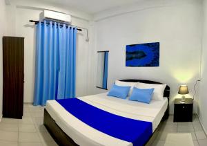 a bedroom with a bed with blue curtains at Mendila Cityscape Hikkaduwa in Hikkaduwa