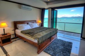 a bedroom with a bed with a view of the ocean at Emerald Beach-Front Apartments Fishermans Village in Koh Samui 