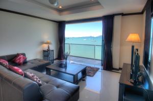 a living room with a couch and a large window at Emerald Beach-Front Apartments Fishermans Village in Koh Samui 