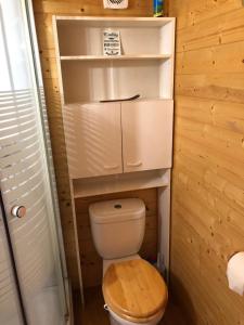 Elle comprend une petite salle de bains pourvue de toilettes et d'un siège en bois. dans l'établissement Chambre studio cuisine indépendant 2 pers piscine, à Rousson