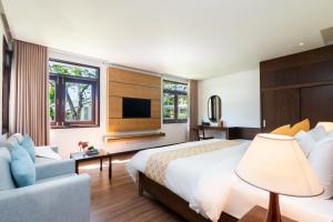 a bedroom with a bed and a tv and a couch at Hoang Ngoc Beach Resort in Mui Ne