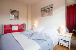 a bedroom with two white beds and a red couch at Sables d'or Bel Appartement 300 m de la plage in Frehel