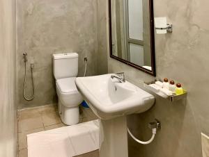 une salle de bain avec un lavabo, des toilettes et un miroir dans l'établissement Mendila Cityscape Hikkaduwa, à Hikkaduwa