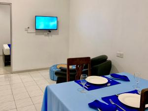 une salle à manger avec une table bleue, des chaises et une télévision dans l'établissement Mendila Cityscape Hikkaduwa, à Hikkaduwa