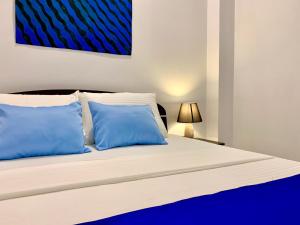 - un lit avec 2 oreillers bleus dans une chambre dans l'établissement Mendila Cityscape Hikkaduwa, à Hikkaduwa