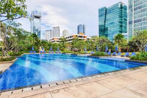 a large swimming pool in a city with skyscrapers at Quarter by Kozystay - Setiabudi in Jakarta