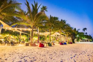 a sandy beach with palm trees and a restaurant at Hoang Ngoc Beach Resort in Mui Ne