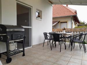eine Terrasse mit einem Grill und einem Tisch mit Stühlen in der Unterkunft Holiday Home Balatonszárszó in Balatonszárszó