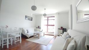 a white living room with a white couch and a table at Apartament Bello - free parking in Gdańsk