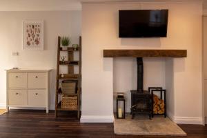 a living room with a fireplace with a tv on a wall at Modern Cottage for Couples, Parking, 3 Min 2 Beach in Beer