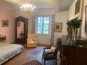 a bedroom with a bed and a chandelier at Le Manoir des Bréholles in Goustranville