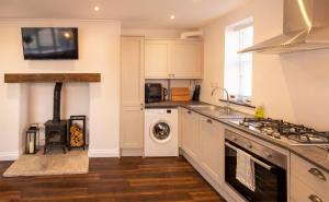 a kitchen with a stove top oven next to a washing machine at Modern Cottage for Couples, Parking, 3 Min 2 Beach in Beer