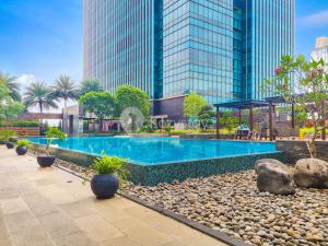 ein Schwimmbad vor einem hohen Gebäude in der Unterkunft BLANC by Kozystay - 1BR Apartment in SCBD in Jakarta