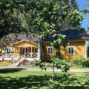 una casa de madera con un árbol delante en Ollilan tupa Joensuun lähellä, en Ylämylly