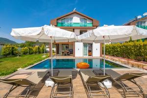 a house with a swimming pool with chairs and umbrellas at 4 Beds, Luxury Holiday Villa in Hisarönü Ölüdeniz Villa Mia in Fethiye