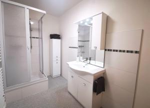 a white bathroom with a sink and a shower at Pension Bergfried in Hallstatt