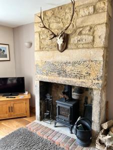 a living room with a stone fireplace with a deer head on the wall at Spaniel Cottage with views of Ham hill, Stoke sub Hamdon in Martock