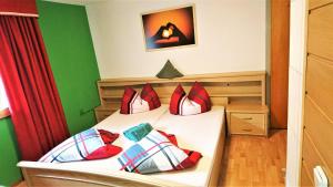1 dormitorio con 1 cama con almohadas rojas y blancas en Klause-Stüberl, en Gaicht