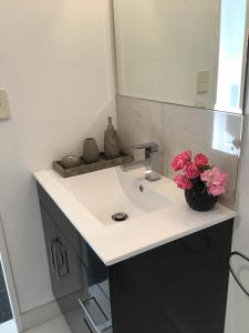 a bathroom sink with a vase of flowers on it at La Casita Waiheke in Oneroa