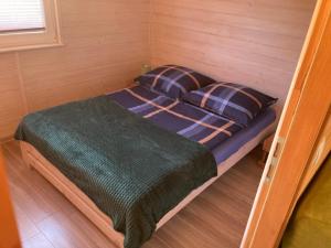 Bett in einem kleinen Zimmer mit grüner Bettdecke und Kissen in der Unterkunft Domek Letniskowy KAL in Angerburg