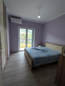 um quarto com uma cama e uma grande janela em Cheerful 2 bedroom villa with free parking. em Gjirokastër