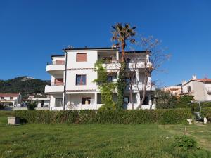 ein weißes Gebäude mit einem Baum auf einem Feld in der Unterkunft Apartments Amfora in Barbat na Rabu