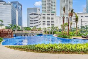 a large swimming pool in a city with tall buildings at M-APLE by Kozystay - 2BR Apartment in Kuningan in Jakarta