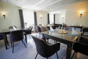 un comedor con mesas, sillas y ventanas en Hotel Klostermühle Siebenborn en Maring-Noviand