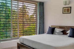 1 dormitorio con cama y ventana grande en Arotel Rooms & Suites, en Calangute