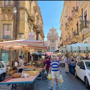 grupa ludzi chodzących po odkrytym rynku w obiekcie Superior Apartment Catania w Katanii