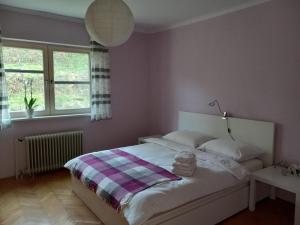 sypialnia z białym łóżkiem i kocem w kratę w obiekcie Lovely 2-bedroom appartment with free parking w mieście Dobrova