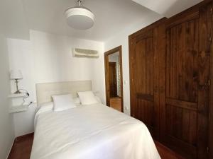 Un dormitorio con una cama blanca y una puerta de madera. en Apartamento Santa Inés, en Granada
