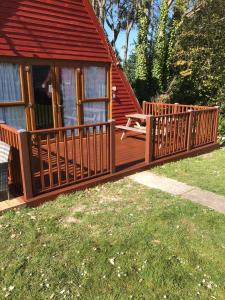 a wooden cabin with a deck and a bench at Seaside Chalet - Sleeps 6 in Kingsdown