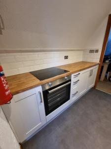 a kitchen with white cabinets and a wooden counter top at Seaside Chalet - Sleeps 6 in Kingsdown