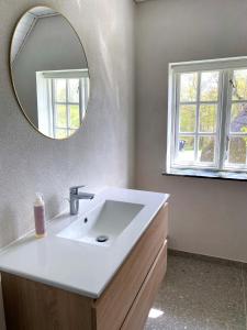 ein Badezimmer mit einem weißen Waschbecken und einem Spiegel in der Unterkunft Gl. Brydegaard in Brydegård