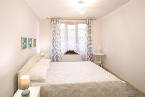 a white bedroom with a bed and a window at Guest House Soirée in Nesebar