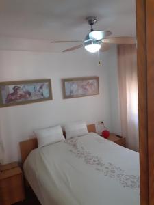 a bedroom with a white bed and a ceiling fan at Apartamento en la playa in Torremolinos