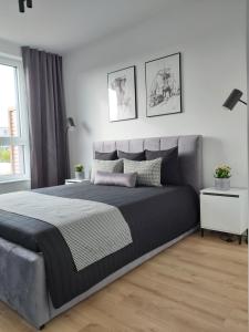 a bedroom with a large bed and a white wall at Apartament 150 Zaspa VVita z ogrodem i tarasem in Gdańsk