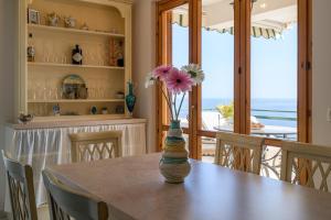 einen Esstisch mit einer Vase mit Blumen darauf in der Unterkunft Ferienhaus Sicilysun Holidays Emilia in Letojanni