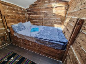 a small bed in a wooden cabin with blue sheets at The Old Nest in Madzharovo